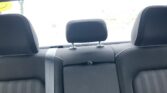 Rear passenger seating area in a car, showing black fabric seats, three headrests, and visible seat belts.