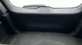 Back interior of a car's cargo area with black carpeting and a curved rear shelf; snow-covered road visible through the rear window.