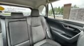 Rear passenger seat of a car with gray fabric upholstery and seat belts, view through the side window showing a dealership lot.