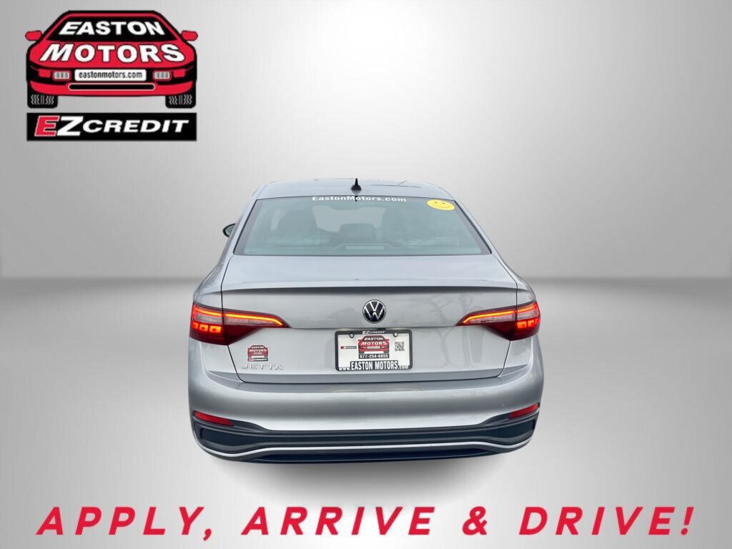 Rear view of a gray VW Jetta with Easton Motors branding on the windshield and the 'APPLY, ARRIVE & DRIVE!' slogan at the bottom of the image.