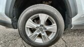 Close-up of a silver alloy wheel and tire on a grey SUV, wheel well visible and tire brand details readable (SureDrive).
