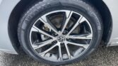Close-up of a car wheel showing a silver alloy rim and tire on a wet asphalt surface.