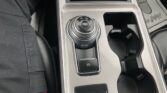 Circular rotary gear selector on a car's center console showing P R N D S with a red indicator, flanked by cup holders and controls