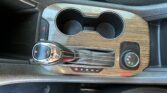 Center console with wooden trim, two cup holders, gear selector to the left, and climate dial on the right edge of the panel.