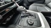 Close-up of a car's center console: automatic gear shifter, mode selector with EV/NORMAL/SPORT, and nearby controls; dashboard display shows climate and 'Passenger Air Bag Off' indicator.
