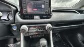 Center dashboard of a car showing a touchscreen infotainment system, hazard button, and dual climate controls.