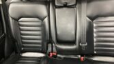 Black leather rear car seats with a fold-down center armrest and two visible red-buckle seat belts.