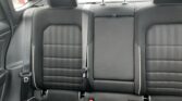 Rear car seats in black fabric with three headrests and visible seat belts.