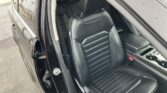 Open car door revealing a black leather front passenger seat with striped stitching and headrest inside the vehicle