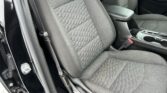 Front interior of a car showing a quilted gray front passenger seat and a center console with cup holders and armrest.