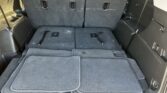 SUV cargo area with the third-row seats folded flat and stacked carpet floor mats in the rear, dark gray interior and trim.