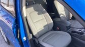 Front interior of a blue car, showing gray fabric seats and a center console with cup holders.