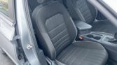 Front interior of a car showing black fabric seats with white stitching and a center console between the seats