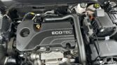 Front view of a car's engine bay with an ECOTEC engine cover, battery, and assorted hoses and wires visible.
