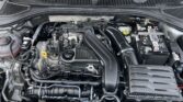 View of a car engine bay with battery on the right, air intake hose center, and various hoses and wiring across the engine compartment.