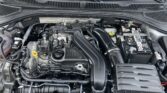 Car engine bay with battery on the right and air intake hose in the center; various hoses and components visible under the hood of a modern vehicle.