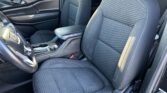 Dark fabric car interior showing front passenger and driver seats with patterned inserts, center console, and door panel.