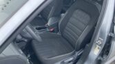 Interior of a car showing the front seats in black fabric with white piping, door open on the passenger side and center console visible