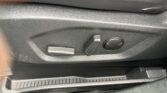 Close-up of a car seat side panel with adjustment levers: a flat rectangular lever, a smaller rounded lever, and a circular dial on black textured plastic.