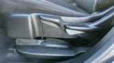 Close-up of a black car seat side with a manual adjustment lever and AIRBAG label on the seat edge