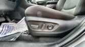 Interior of a car showing the front seat with side adjustment controls, center console, and a plastic-covered floor mat in front.