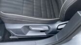 Dark fabric car seat with light piping and horizontal stripes, showing the seat edge and a side adjustment lever near the door sill