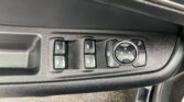 Driver-side control panel with four window buttons, a circular mirror-adjustment knob, and a window lock icon on the door.