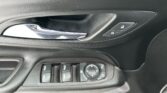 Close-up of a car's interior door: chrome handle, lock/unlock buttons, and a set of window controls on a black panel.