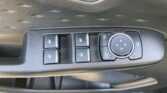 Car door control panel featuring four window switches and a circular multi-directional joystick for adjusting side mirrors, with a window lock button nearby.
