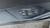 Interior of a car door showing window controls (four switches), a central door lock button, and a circular mirror/seat adjustment dial.