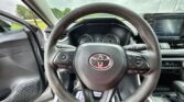 Interior view from the driver’s seat showing a brown steering wheel with Toyota logo, instrument cluster behind, and a center touchscreen.