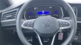 Steering wheel view from the driver seat with digital gauge showing 0 and blue backlight in the instrument cluster, parking lot outside the windshield.