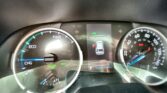 Close-up of a car dashboard: left gauge shows ECO/CHG with READY indicators, right gauge is the speedometer up to 140 mph, center screen displays a green EV icon and a car graphic with gear/odometer readout (112,554 miles).