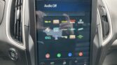 Infotainment touchscreen in car showing Audio Off with app icon grid and climate controls below