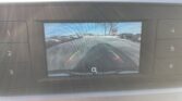 Rearview camera feed showing a parking lot behind the car with green, yellow, and red guiding lines for reversing.