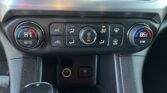 Center console climate controls: dual temperature dials (left HI AUTO, right 65 SYNC), central fan knob, A/C and defrost buttons, gear shifter visible in foreground.