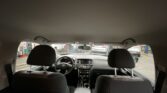 Interior of a car as seen from the back seat, with dashboard and front seats; through the windshield a service bay with cars outside