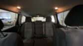 Interior of a car viewed from the back seat, with overhead lights on and gray fabric seats visible in dim lighting