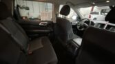 Interior of a car viewed from the backseat, with headrests and center console, garage/workshop visible outside the windows.