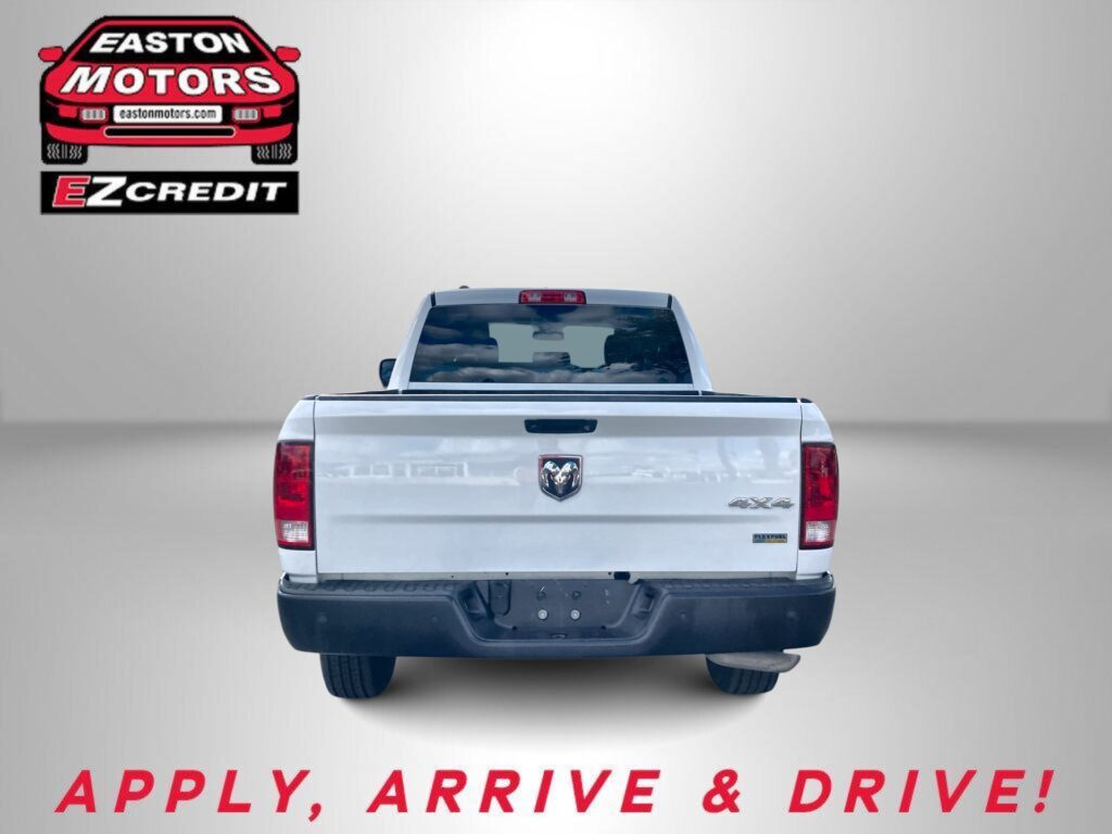 Rear view of a white pickup truck with an EZ Motors EZ Credit logo in the top-left corner on a gray background; bottom text reads "APPLY, ARRIVE & DRIVE!"