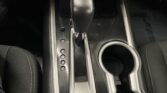 Center console of a car showing an automatic gear shift, cup holders, and a brushed metal trim panel with multiple gear indicator buttons (P, R, N, D).