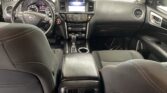 Front interior of a black leather SUV: view from back seat showing steering wheel, center touchscreen, and climate controls between plush seats.