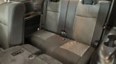 Rear passenger row in a car with three seats, headrests, and visible seat belts; view from the trunk area looking toward the back seats, black and gray fabric upholstery.