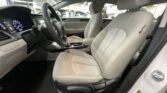Front interior of a car with light gray seats, steering wheel, and center console visible in the cabin.