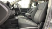 Interior of a car's front cabin showing the steering wheel, driver and passenger seats, and center console in a garage setting.