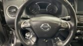 Steering wheel with Nissan logo centered, dashboard gauges behind, and left air vent visible in a car interior