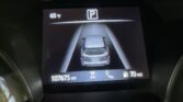 Infotainment screen showing rear parking view with a 'P' icon, car centered between lane guides, outside temp 65°F, and mileage 107,675 miles.