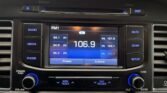In-car stereo head unit showing FM1 at 106.9 with preset options on screen and blue-lit control buttons.