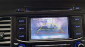 Infotainment screen showing a reverse camera view with yellow guide lines behind the car in a parking lot