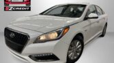 White sedan shown in a studio with Easton Motors EZ Credit logo to the left and 'APPLY, ARRIVE & DRIVE!' slogan at the bottom